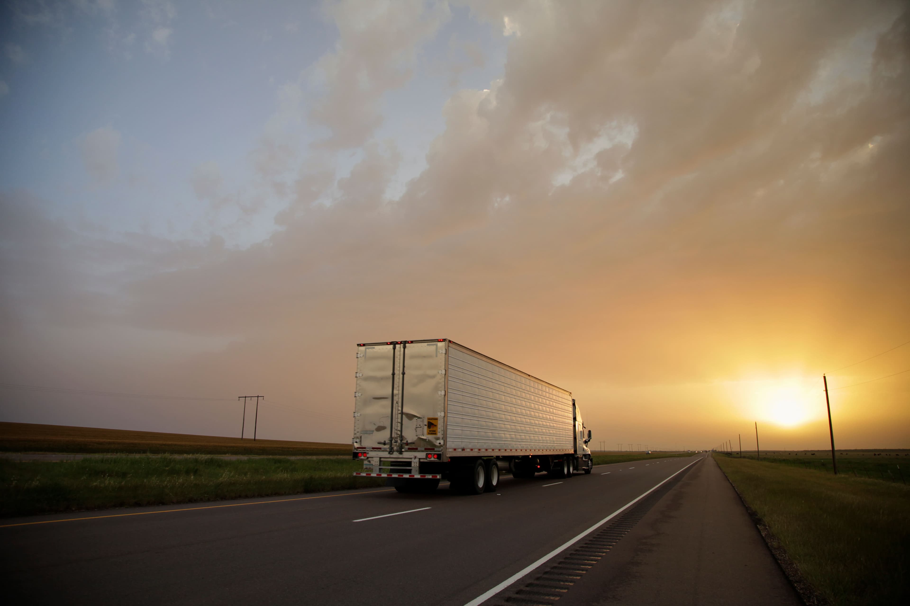 Truck driving on a country road with sunset