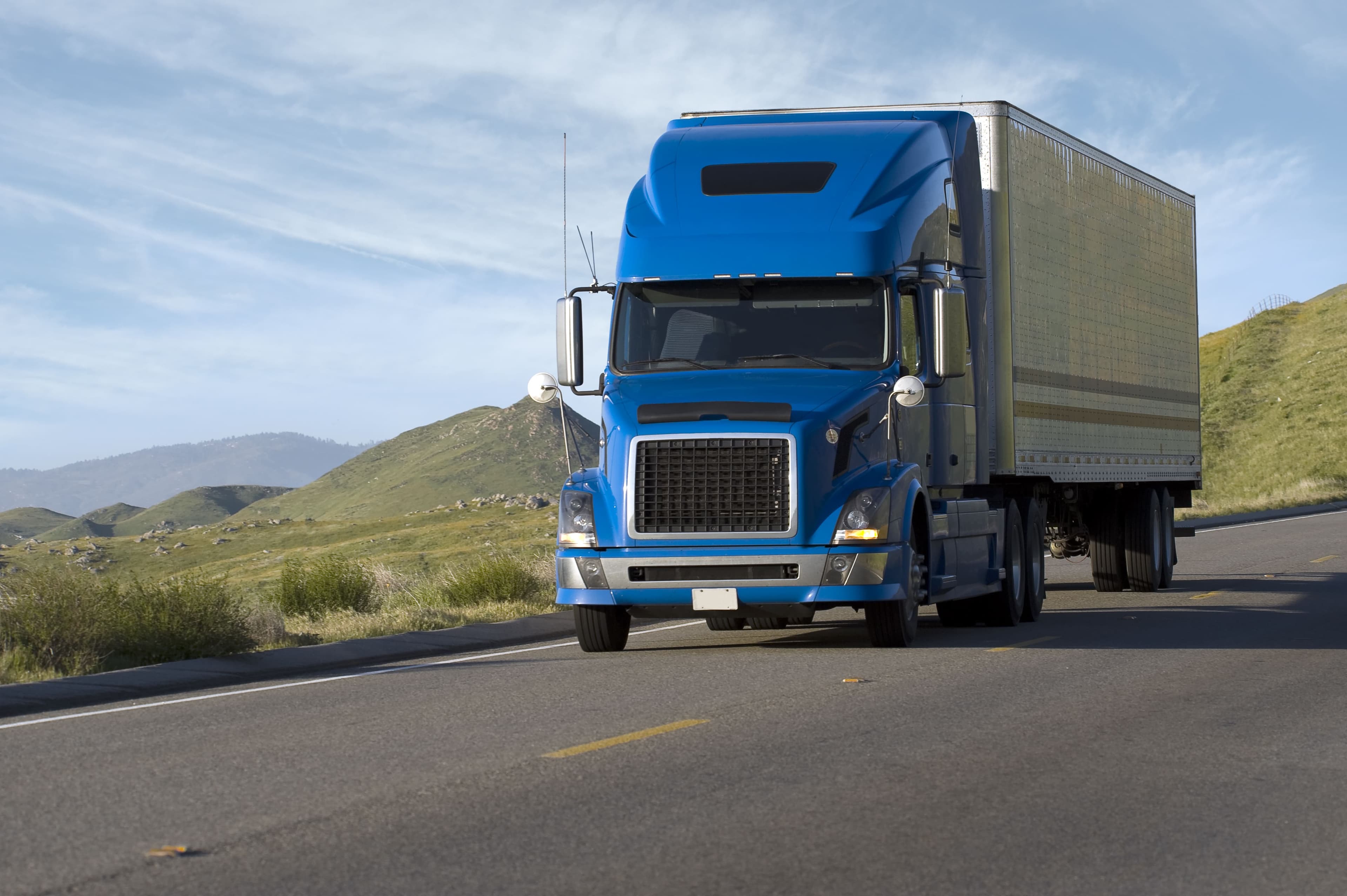 Truck driving on a road with a mountain background