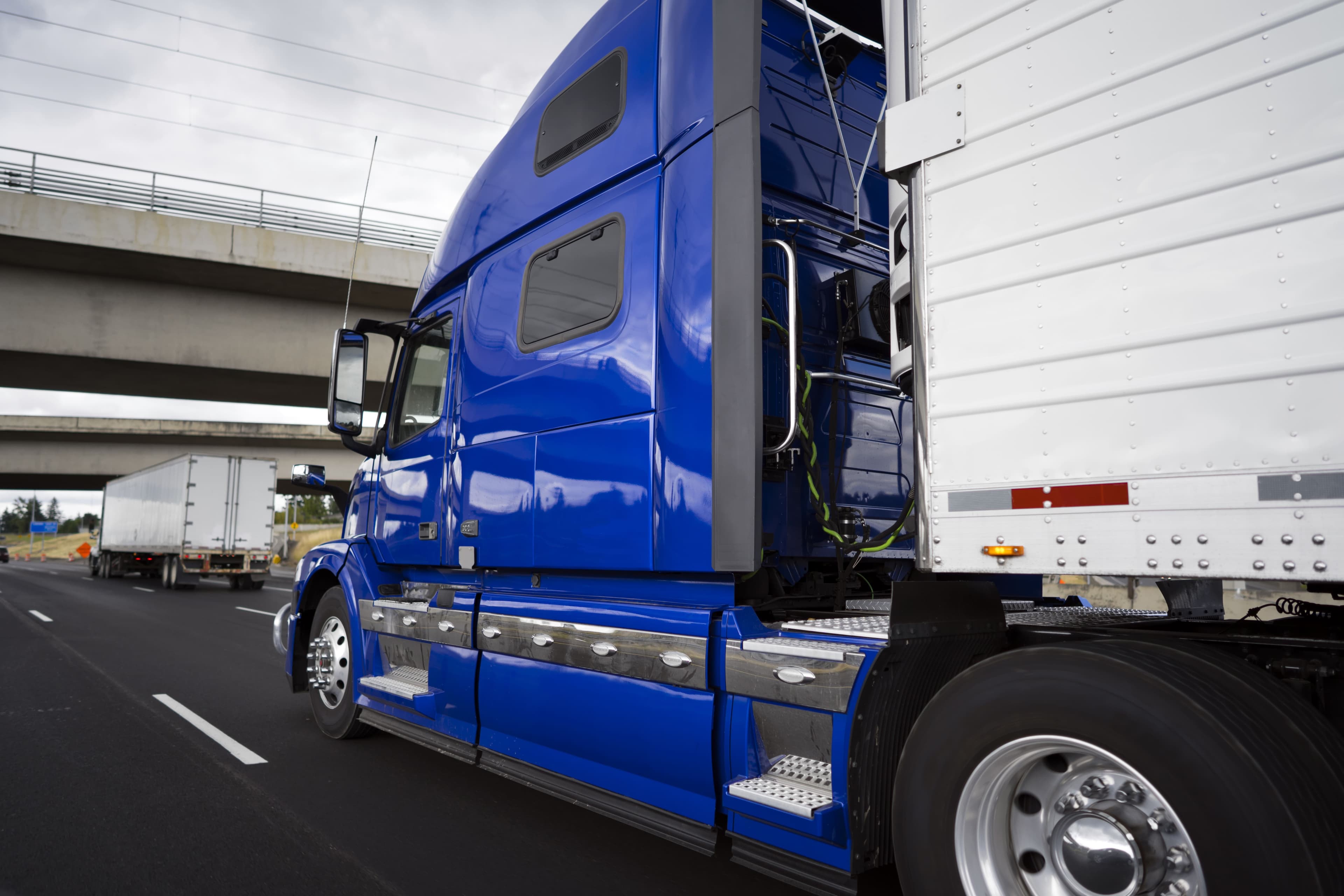 Blue truck driving under a bridge